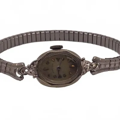 Sale Photo Thumbnail #8: Vintage women's Hamilton cocktail watch featuring an oval face with decorative scroll lugs and a metallic stretch band.
