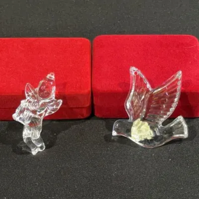 Sale Photo Thumbnail #87: Two clear glass Christmas ornaments depicting a cherub and a dove in flight, accompanied by red velvet presentation boxes.