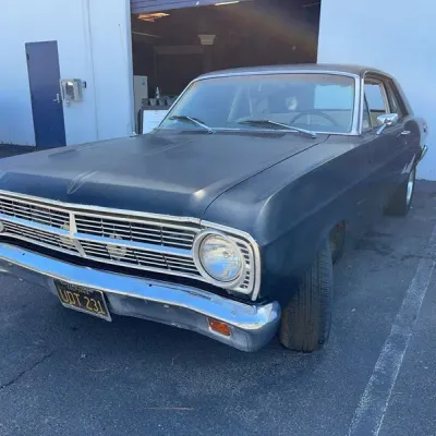 Sale Photo Thumbnail #2: Vintage dark blue late-1960s Ford Falcon two-door coupe featuring chrome trim and California black license plates.