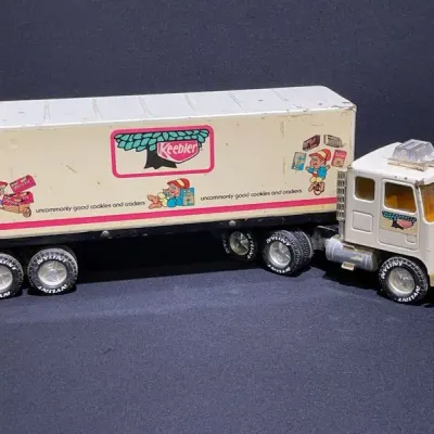 Sale Photo Thumbnail #24: Vintage Nylint pressed-steel Keebler semi-truck and trailer toy, featuring colorful printed graphics and showing minor play wear.
