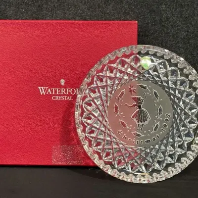 Sale Photo Thumbnail #81: Waterford Crystal 1992 annual Christmas plate with cut glass rim and central frosted figure depiction, accompanied by its original red presentation box.
