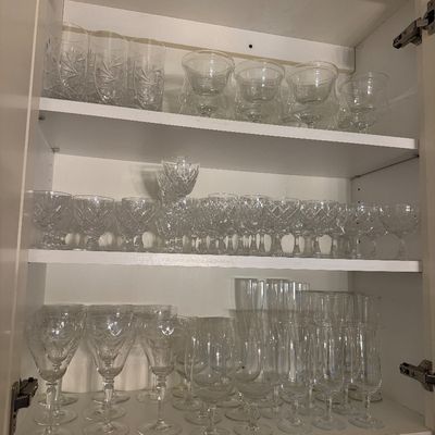 Sale Photo Thumbnail #38: White kitchen cabinet filled with various collections of cut crystal and glass stemware, including wine glasses, champagne flutes, and highballs.