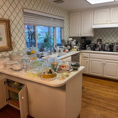 Sale Photo Thumbnail #41: Large assortment of vintage kitchenware and glassware displayed on white kitchen countertops, including Pyrex, CorningWare, pots, pans, and serving dishes.