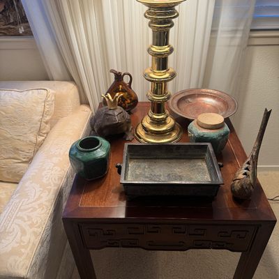 Sale Photo Thumbnail #12: Collection of decorative Asian-style homewares and metal accents displayed on a dark wood end table next to a brass candlestick lamp.