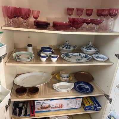 Sale Photo Thumbnail #35: Cabinet shelves organized with ruby red glassware, vintage blue and white ceramic dishware, small stoneware bowls, and kitchen storage items.