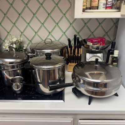 Sale Photo Thumbnail #22: Collection of stainless steel cookware, including stock pots, an electric skillet, and a small butter warmer, set alongside a knife block.