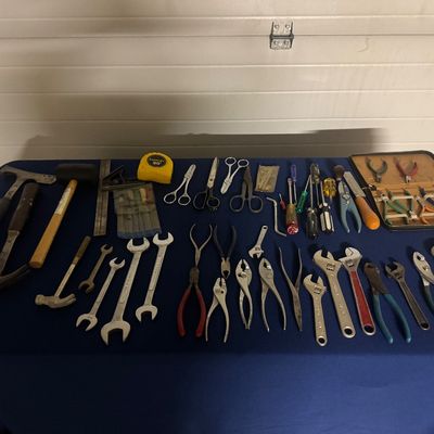 Sale Photo Thumbnail #73: Large collection of vintage hand tools including hammers, wrenches, pliers, screwdrivers, scissors, and a precision tool kit arranged on a table.