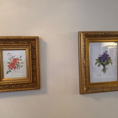 Sale Photo Thumbnail #10: Pair of framed vintage botanical prints featuring pink roses and purple violets, displayed in ornate carved gilt frames.