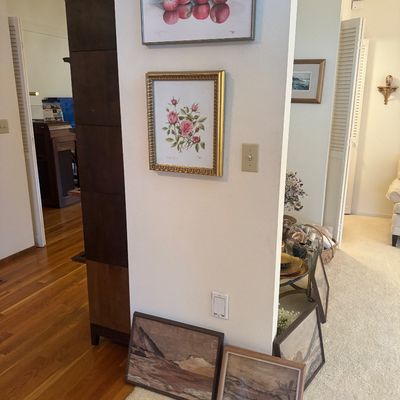 Sale Photo Thumbnail #7: A collection of framed art pieces, including botanical and still-life prints hung on the wall, alongside landscape paintings. 