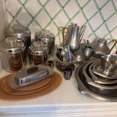 Sale Photo Thumbnail #37: Collection of mid-century stainless steel and pewter tableware, including a four-piece canister set with clear knobs, serving trays, teapots, and a butter dish.