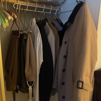 Sale Photo Thumbnail #70: Selection of men's outerwear, dress shirts, and slacks hanging in a closet, including a double-breasted trench coat.