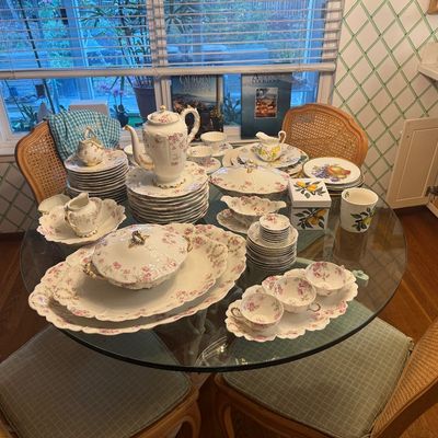 Sale Photo Thumbnail #40: Large vintage Haviland Limoges fine porcelain dinnerware service featuring delicate floral patterns and gilded accents, displayed on a glass-top dining table.