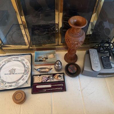 Sale Photo Thumbnail #14: Collection of home goods including a Royal Worcester boxed plate, a Bose Wave music system with remotes, a carved wood vase, costume jewelry, and various small decorative trinkets.
