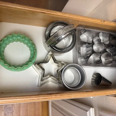 Sale Photo Thumbnail #31: Collection of assorted vintage cookie and biscuit cutters, including metal star shapes, round metal cutters with handles, a green plastic fluted cutter, and a boxed set of mini stainless steel shapes.