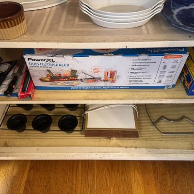 Sale Photo Thumbnail #33: Cabinet shelves containing a boxed PowerXL Duo NutriSealer, plastic wrap, a muffin tin, ceramic ramekins, and various kitchen items.