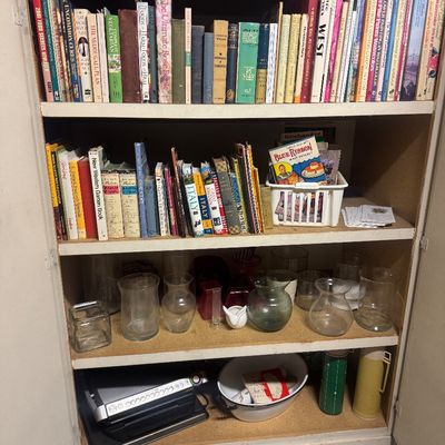 Sale Photo Thumbnail #77: Wooden cabinet filled with books on various topics, glass vases, kitchen items, and vintage thermoses across four shelves.