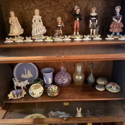 Sale Photo Thumbnail #49: Collection of decorative porcelain figurines and vintage pottery displayed inside a wooden barrister bookcase, including Wedgwood jasperware and hand-painted art glass.