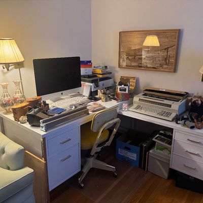 Sale Photo Thumbnail #64: Home office setup featuring a modern white corner desk, an Apple iMac, a vintage electric typewriter, lamps, and various office supplies.