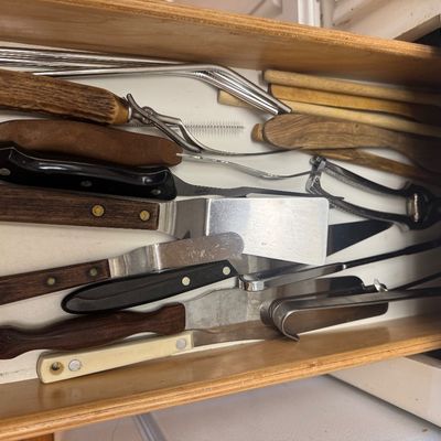 Sale Photo Thumbnail #32: Wooden kitchen drawer filled with an assortment of utensils, including spatulas, knives, stainless steel straws, and wooden tools.
