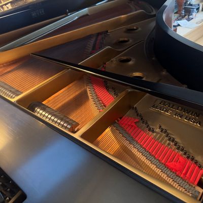 Sale Photo Thumbnail #5: Interior view of a Baldwin grand piano showing the soundboard, strings, and cast-iron plate with "Baldwin Made in USA" lettering.