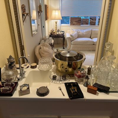Sale Photo Thumbnail #46: A collection of barware items set on a wet bar, including cut crystal decanters, a brass ice bucket, coasters, and accessories.