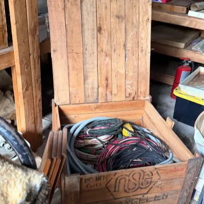 Sale Photo Thumbnail #19: Vintage NSG wooden shipping crate with an attached lid, filled with assorted electrical wiring and flexible conduit.
