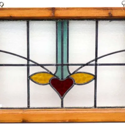 Sale Photo Thumbnail #25: Vintage stained glass window featuring a geometric heart motif with red, amber, and teal accents, set in a wood frame with hanging eyelets.