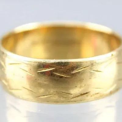 Sale Photo Thumbnail #14: Vintage wide gold wedding band featuring engraved slash details along the outer surface.