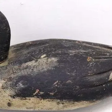 Sale Photo Thumbnail #19: Vintage hand-carved wooden duck decoy featuring a distressed, heavily worn paint finish in black and off-white.