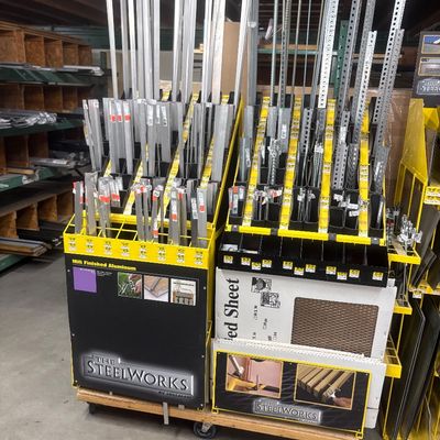 Sale Photo Thumbnail #26: The SteelWorks rolling metal stock display rack, stocked with various aluminum and steel bars, angles, threaded rods, and perforated metal sheets.