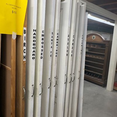 Sale Photo Thumbnail #77: Sliding display rack of sample interior doors in various styles and finishes, priced at $10 each.