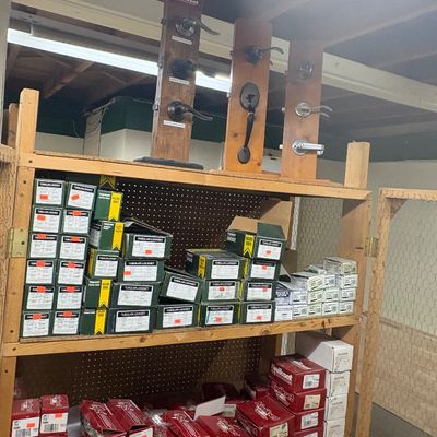 Sale Photo Thumbnail #89: Shelving unit filled with boxed Kwikset door hardware and locksets, featuring mounted door handle displays on the top shelf.