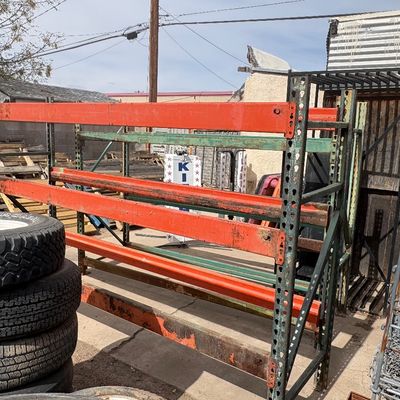 Sale Photo Thumbnail #45: Heavy-duty industrial pallet racking with orange crossbeams and green upright frames, showing surface wear and weather exposure.