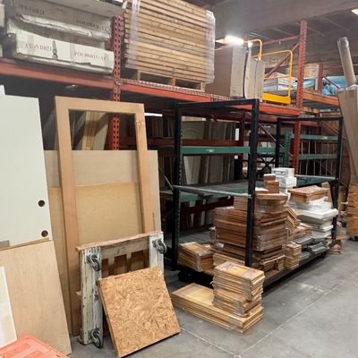 Sale Photo Thumbnail #87: Warehouse filled with building supplies, featuring stacks of lumber, cabinet door fronts, plywood, and various construction materials on industrial shelving.