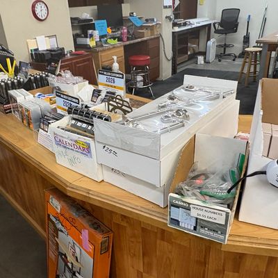Sale Photo Thumbnail #18: Wooden checkout counter display featuring various retail smalls, packaged hardware items, calendars, flashlights, and house numbers.