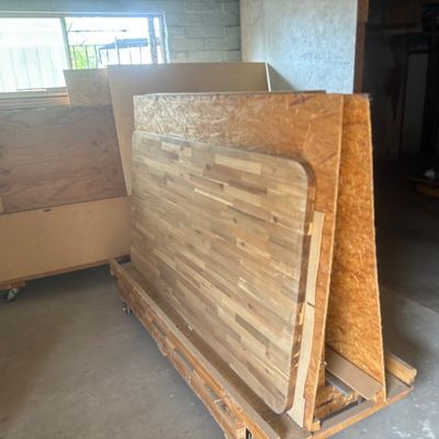 Sale Photo Thumbnail #46: Assorted lumber, butcher block wooden tabletop, and OSB panels stored on rolling A-frame carts in a workshop.