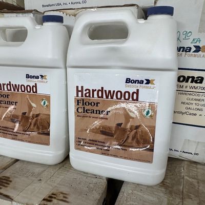 Sale Photo Thumbnail #29: Two 1-gallon plastic jugs of Bona Hardwood Floor Cleaner resting on cardboard shipping boxes.