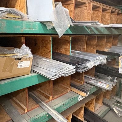 Sale Photo Thumbnail #76: Industrial green metal shelving unit filled with organized hardware materials, door thresholds, and aluminum extrusions.