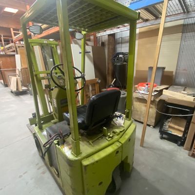 Sale Photo Thumbnail #4: Vintage green industrial electric forklift with an overhead guard, black vinyl seat, and dual side mirrors, showing light cosmetic wear.