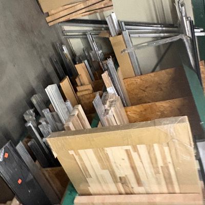 Sale Photo Thumbnail #75: Assorted lumber, wood planks, and metal extrusions organized on storage racking in a workshop setting.