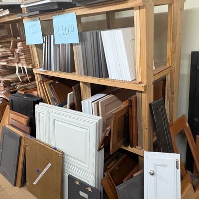 Sale Photo Thumbnail #27: Large assortment of replacement cabinet doors and drawer fronts in various finishes and styles, organized on wooden shelving units.