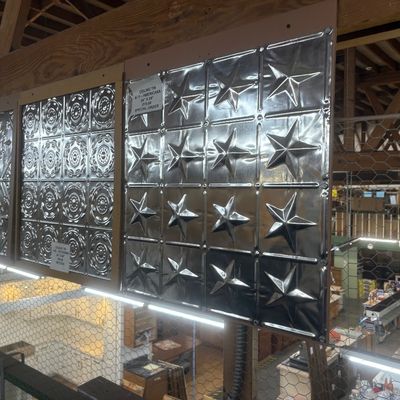 Sale Photo Thumbnail #32: Display panels featuring pressed tin ceiling tiles in various embossed patterns, including star and floral medallion motifs.