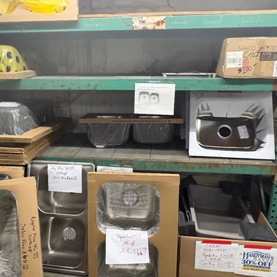 Sale Photo Thumbnail #88: Selection of new stainless steel and composite kitchen sinks, boxed and priced on industrial shelving.