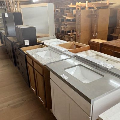 Sale Photo Thumbnail #39: Selection of modern bathroom vanity cabinets with integrated stone countertops and sinks in various wood and painted finishes.