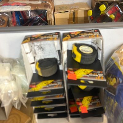 Sale Photo Thumbnail #10: Two retail display boxes containing modern yellow and black retractable tape measures alongside various hardware items.