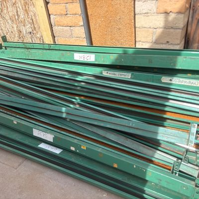 Sale Photo Thumbnail #49: Large stack of heavy-duty green metal pallet rack cross beams, showing some surface wear and handwritten labels.