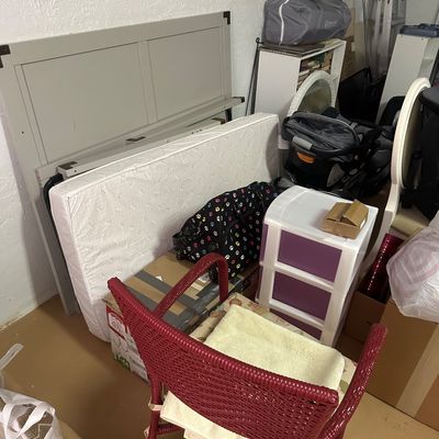 Sale Photo Thumbnail #28: Collection of household goods including a red wicker armchair, plastic storage drawers, a crib mattress, and a grey wooden headboard frame.