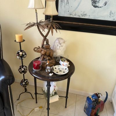 Sale Photo Thumbnail #13: Round dark wood side table featuring a palm tree and elephant motif double-light table lamp alongside various animal figurines and decor.