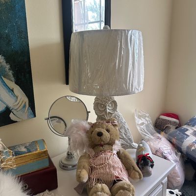 Sale Photo Thumbnail #75: A dressed teddy bear sitting on a nightstand in front of an owl-shaped table lamp with a wrapped shade. Surrounding items include a vanity mirror, decorative boxes, and plush toys.