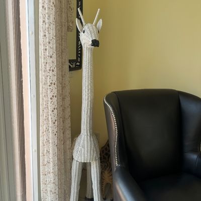 Sale Photo Thumbnail #11: Tall white woven wicker giraffe floor sculpture paired with a black leather wingback armchair featuring nailhead trim.